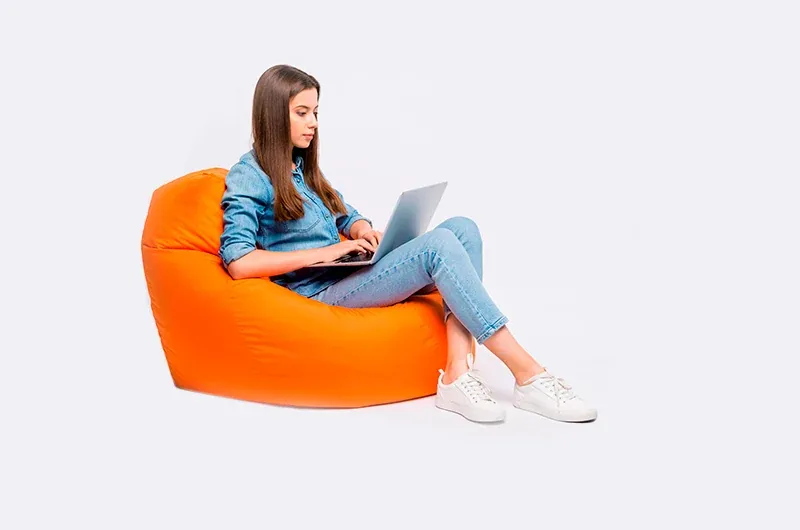 Mulher sentada em um pufe usando um notebook para treinar em casa com a CogniFit
